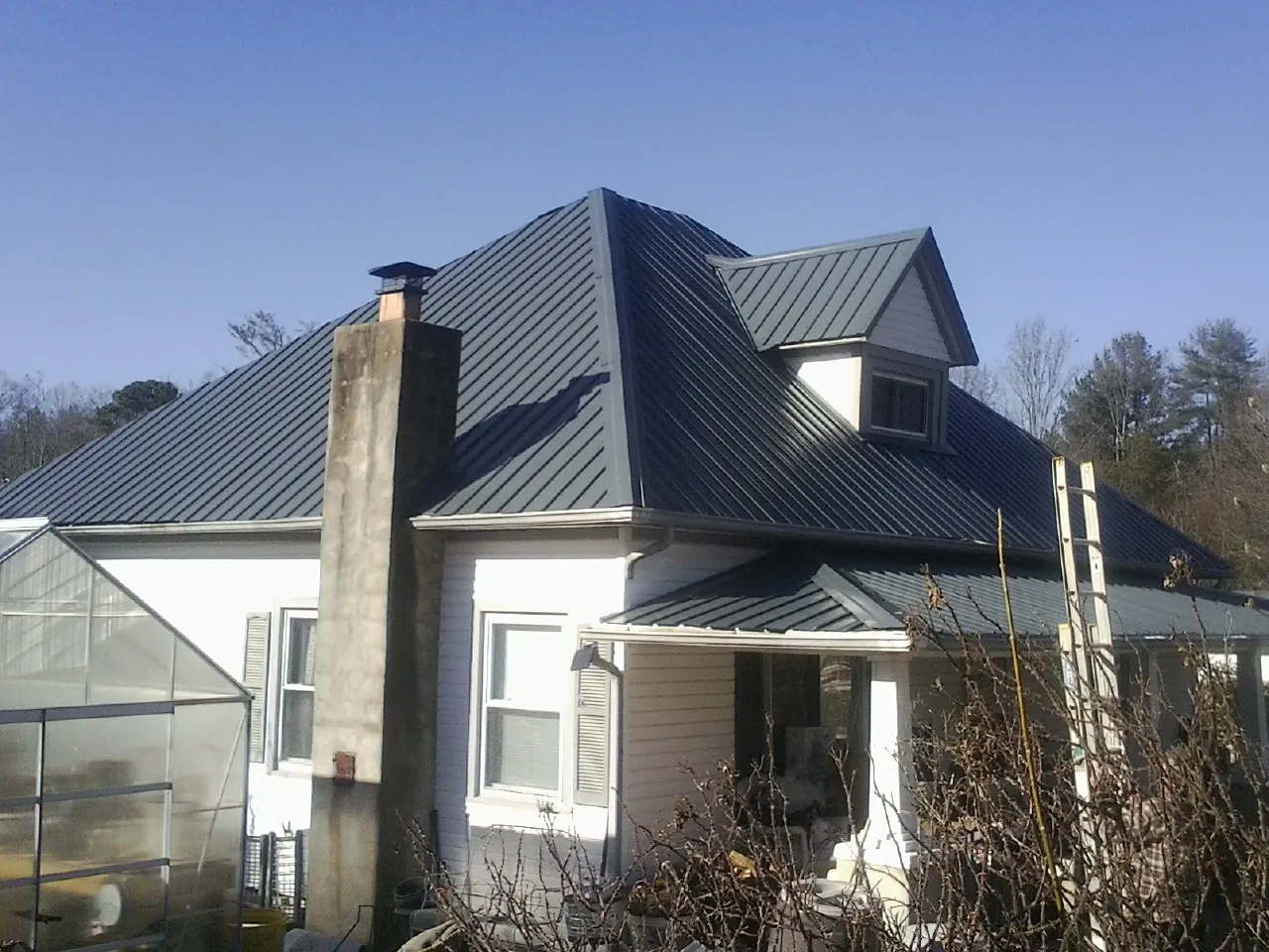 Dark blue standing seam metal roof on a white farmhouse with dormer — Slate & Tile Roof Repair by Roofing Brothers in Hickory