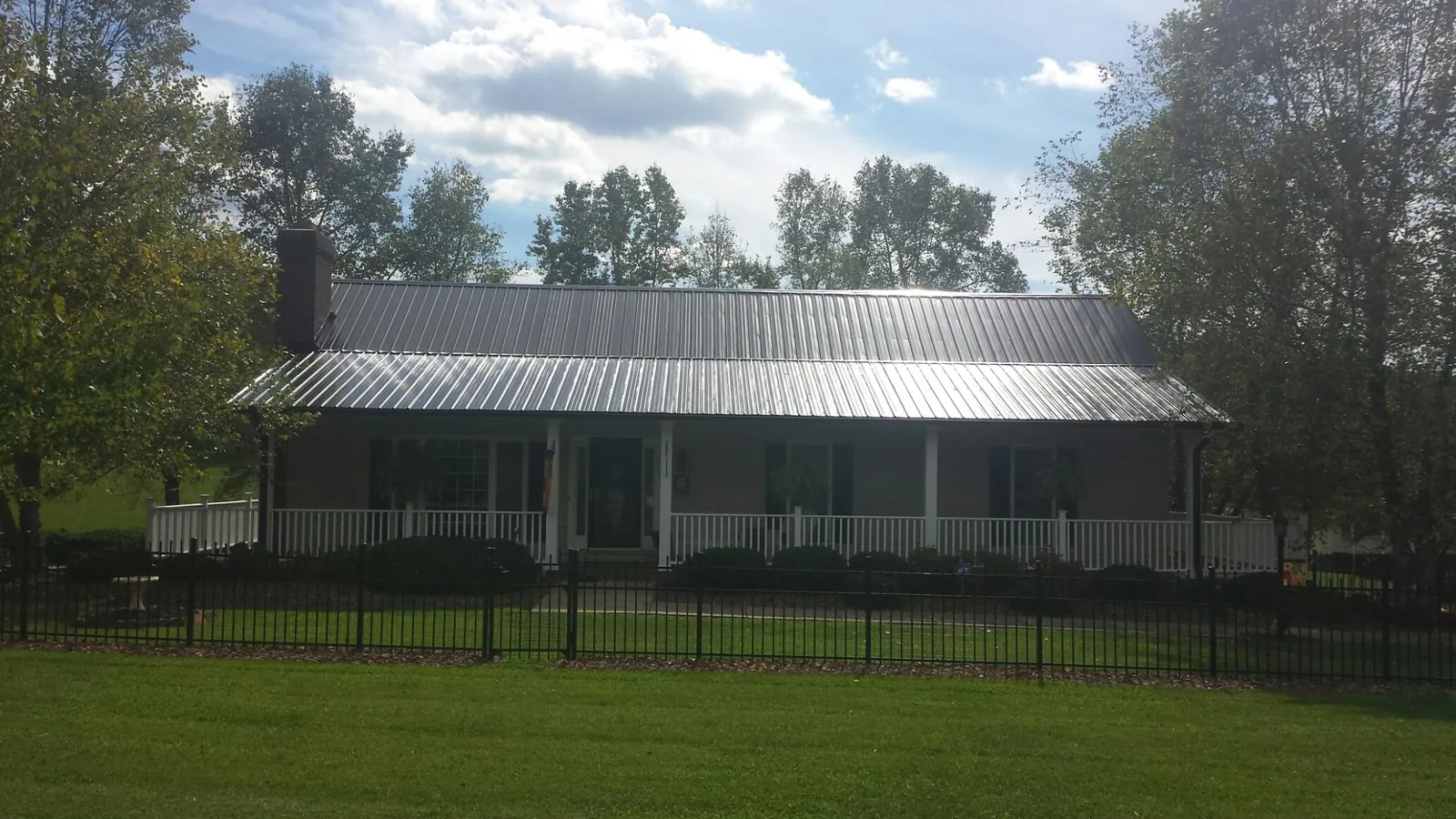 Gray metal roof on a brick ranch with a full width front porch — Gutter Guard Installation work by our crew in Hickory