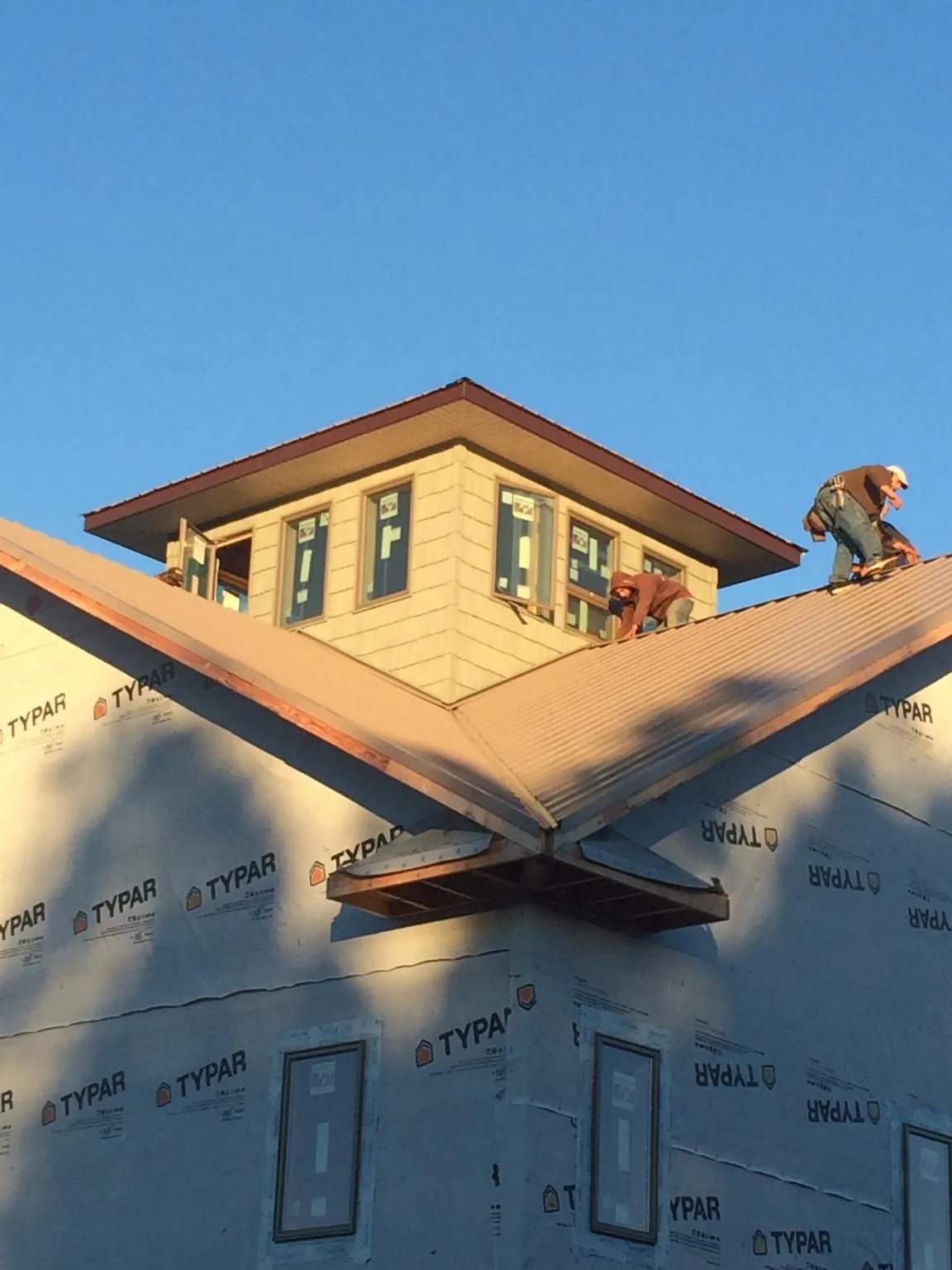 Roofers working around a rooftop cupola on a new metal roof at sunset — Roof Waterproofing in Hickory by Roofing Brothers